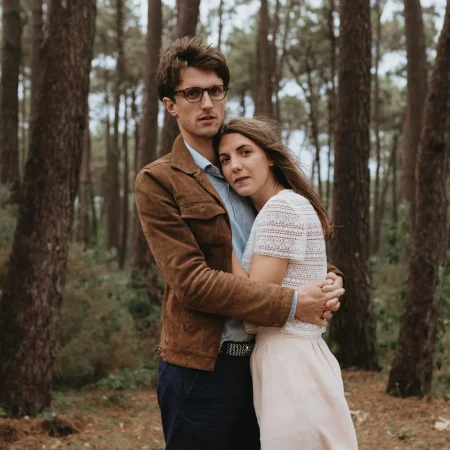 Couple enlacé pendant leur séance engagement dans une forêt de pins