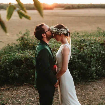 Couple de mariés devant le coucher de soleil (golden hour), avec une couronne de fleurs