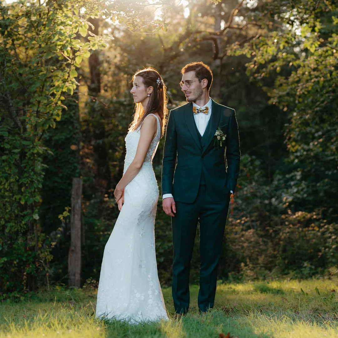Un couple de mariés dans un jardin devant le soleil de fin d'après-midi