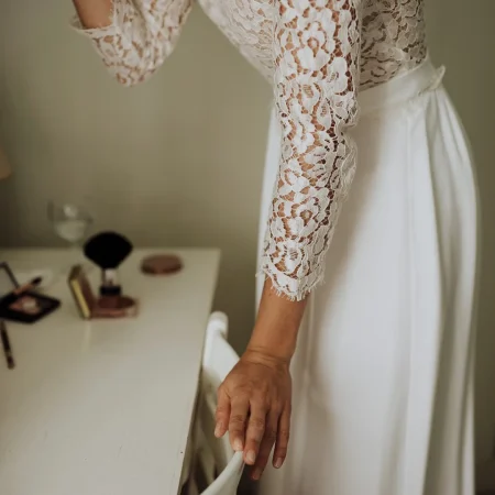 Une mariée se maquillant, focus sur la dentelle de sa robe