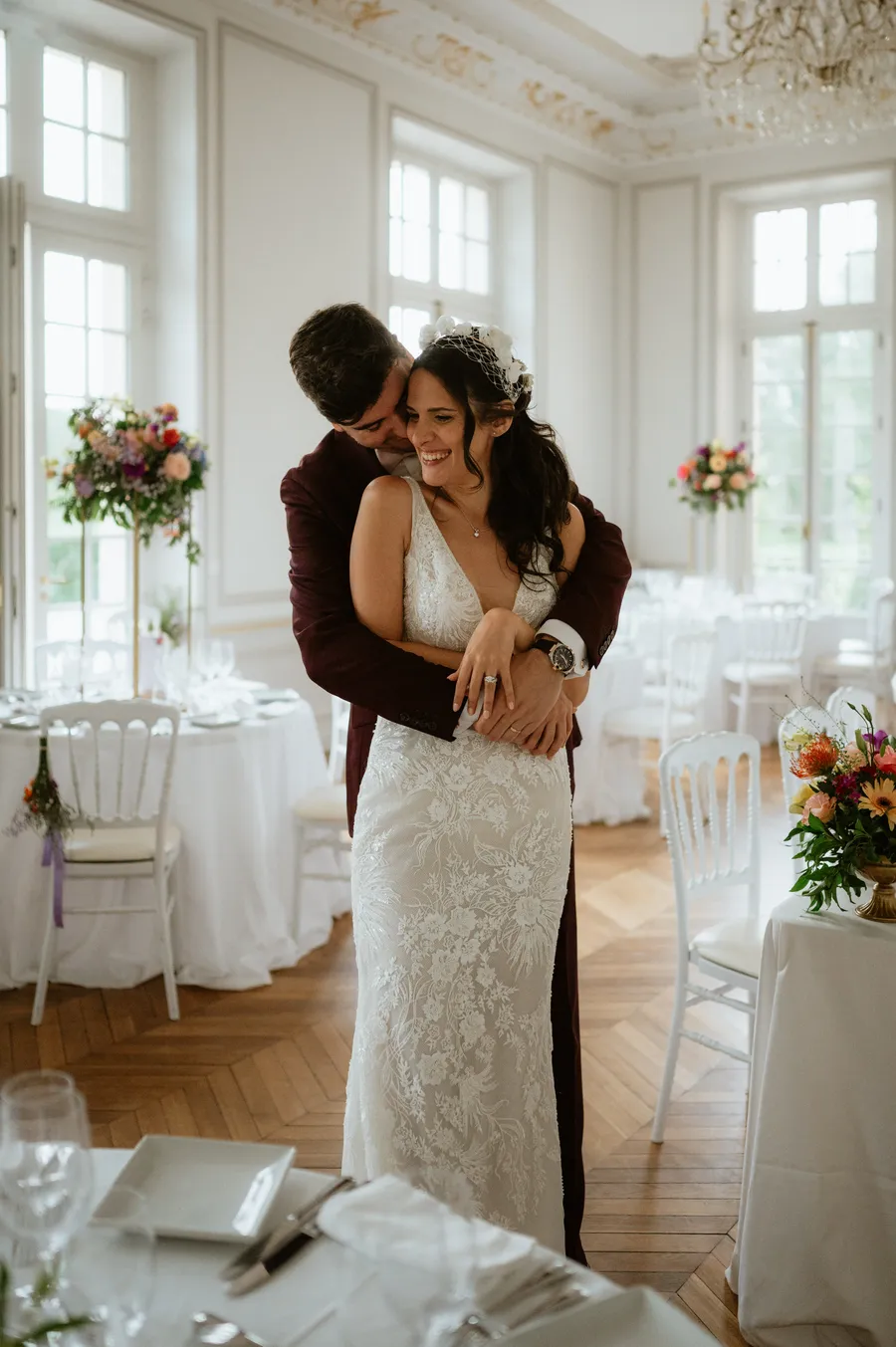 Un couple de mariés souriants enlacé dans la salle de dîner de leur mariage