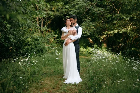 Un couple de mariés enlacés le jour de leur mariage dans un jardin luxuriant dans le Marais poitevin