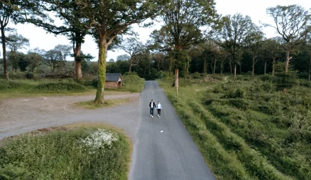 Un couple vu de drone marchant sur une route au milieu de la forêt de Mervent