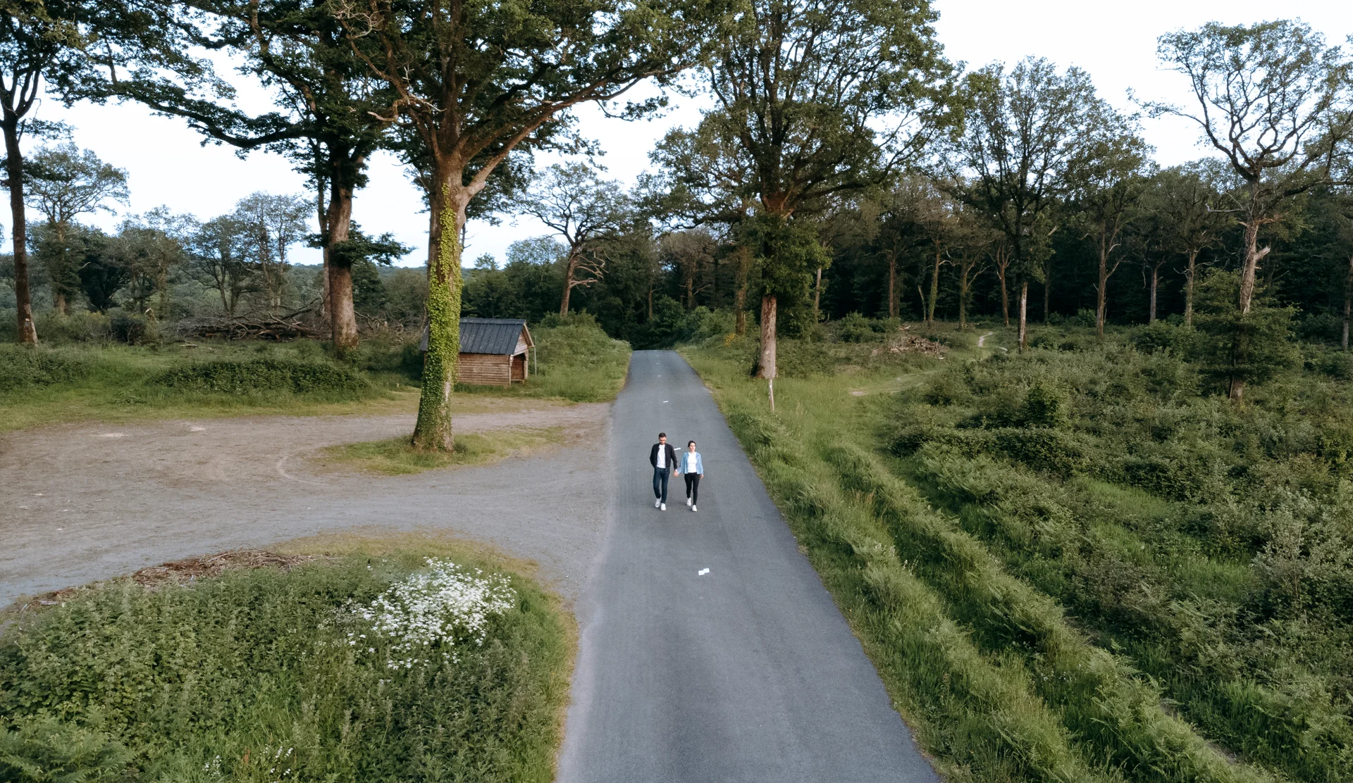 Un couple vu de drone marchant sur une route au milieu de la forêt de Mervent