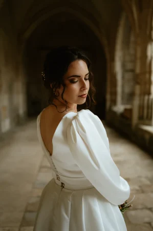 Une mariée posant de dos dans sa robe dans le cloître de la cathédrale de Luçon