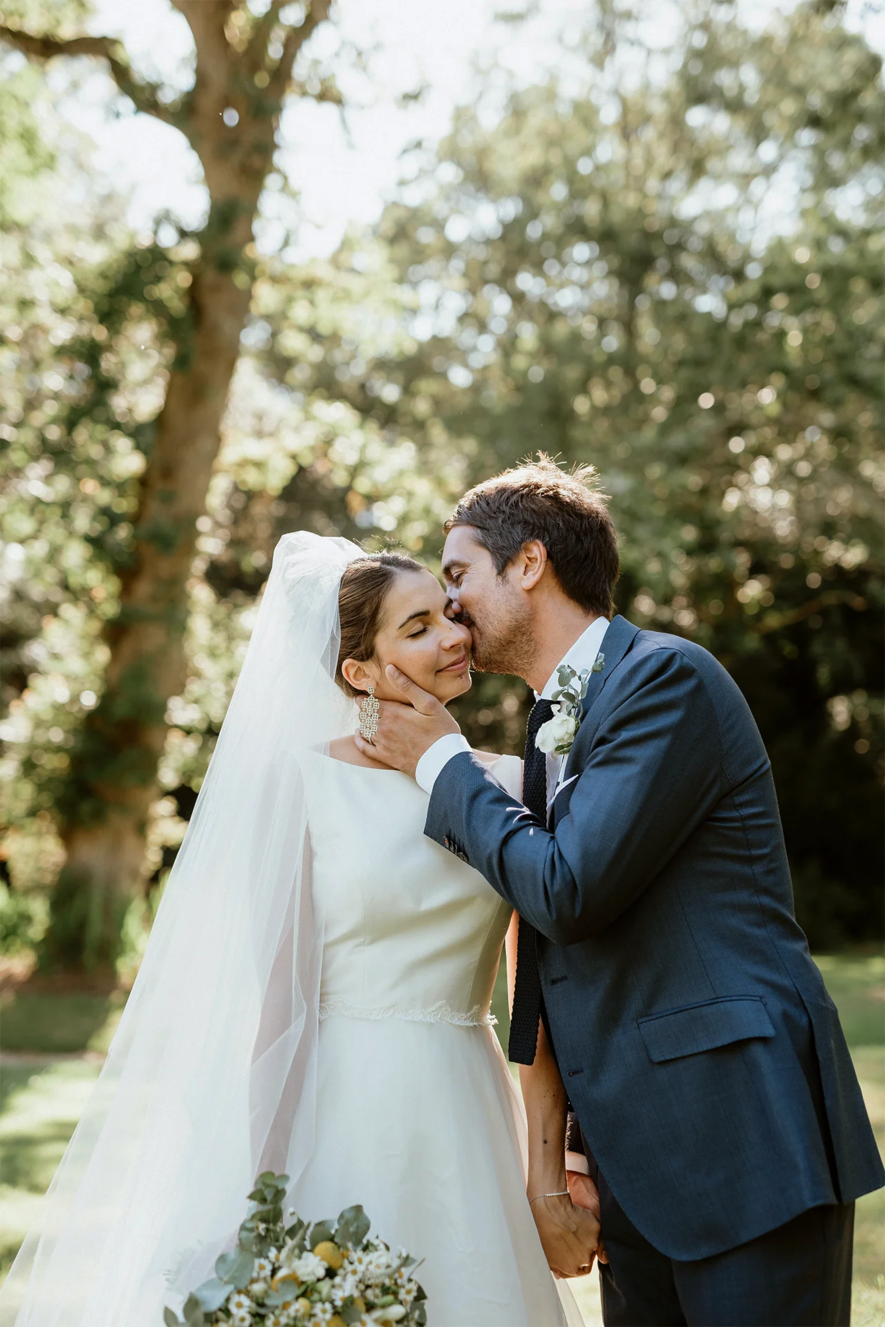 Un couple s'embrasse dans un jardin au Château de Lauvergnac en Loire-Atlantique le jour de leur mariage