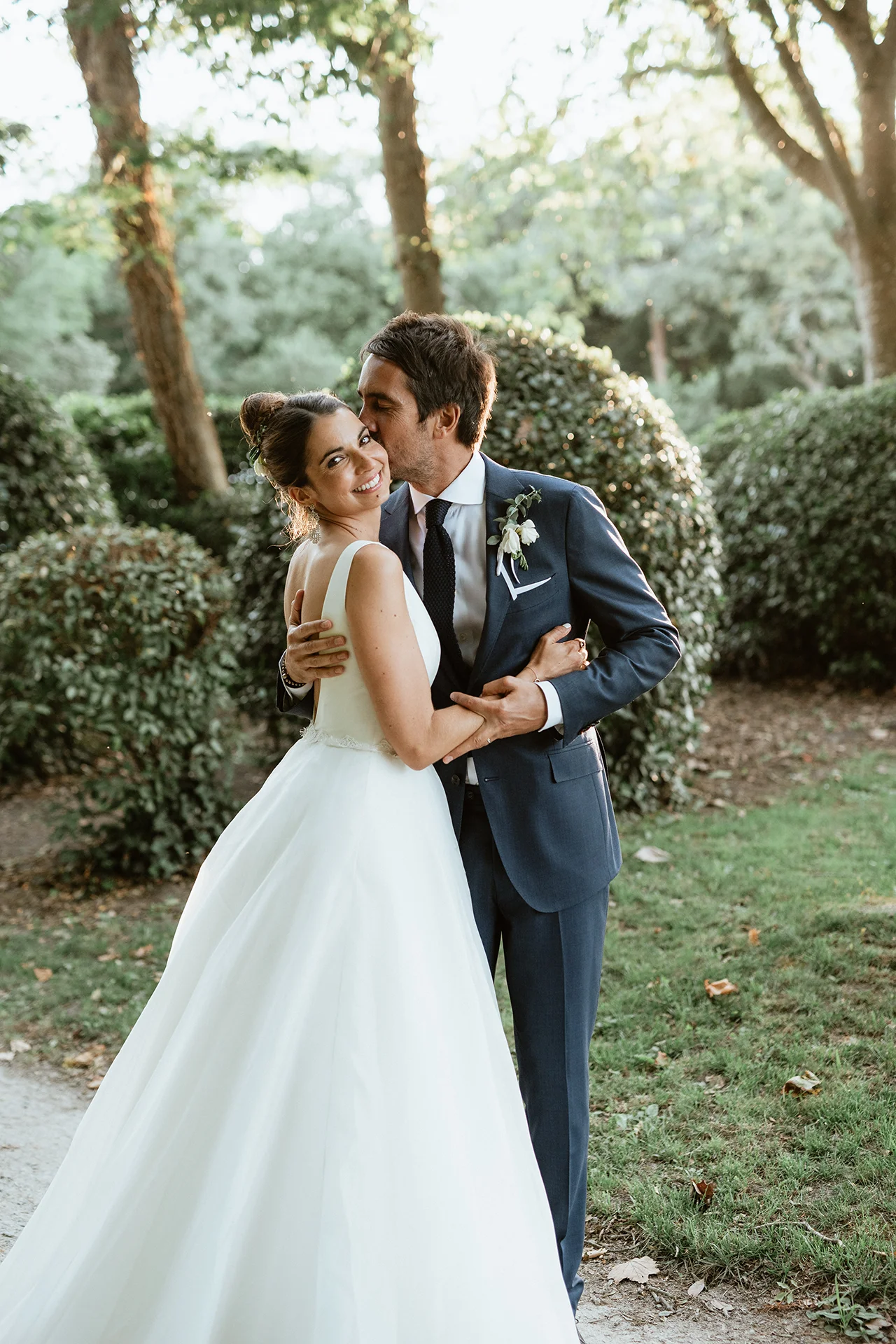 Couple s'enlace et s'embrasse le jour de leur mariage dans un jardin au Château de Lauvergnac